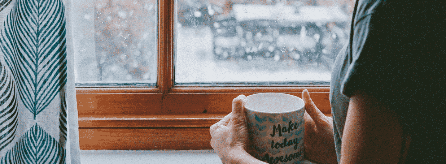 femme avec une tasse devant une fenêtre